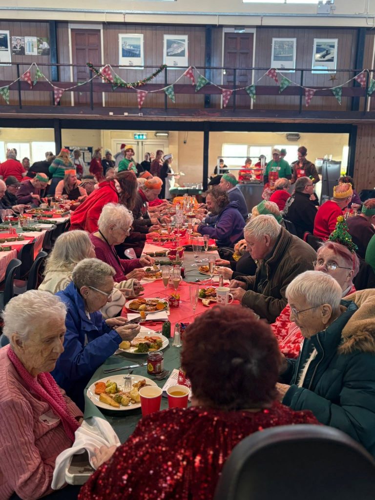 Guests seated together around Christmas dinner tables in a busy hall