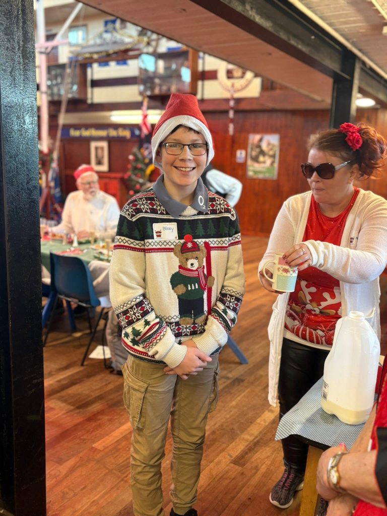 Volunteer in a Santa hat carrying gifts through the hall